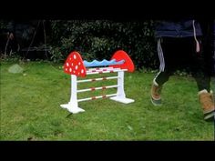 a toy horse jumping over an obstacle in the grass