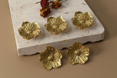 four gold flower shaped knobs sitting on top of a marble block