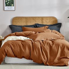 a bed with an orange comforter and pillows