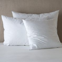 two white pillows sitting on top of a bed next to each other in front of a headboard