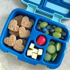 a blue lunch box filled with fruit and crackers next to a container of cheese