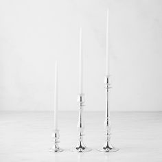 three white candles sitting next to each other on top of a marble floored surface