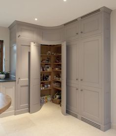 an open pantry in the middle of a kitchen with lots of cupboards and shelves