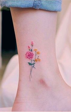 a small flower tattoo on the ankle with yellow and pink flowers in between it's petals