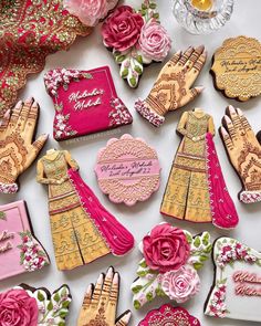 decorated cookies are arranged on a table with pink and gold decorations, including hendikes