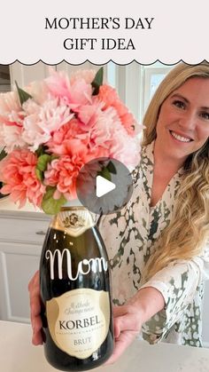 a woman holding up a bottle of wine with flowers in it and the words mother's day gift idea