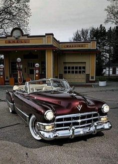 an old fashioned car parked in front of a gas station with a clock on the wall