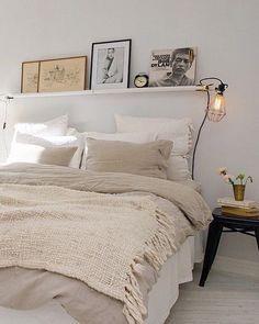 a bed with white linens and pillows in a bedroom next to a lamp on a table