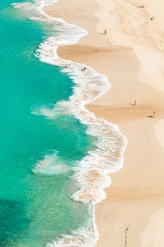 an aerial view of the beach and ocean with people on it, taken from above