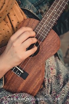 a person is playing an ukulele with their hand on the guitar strings and holding it