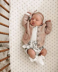 a baby laying on top of a bed next to a crib