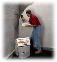 a man in red shirt and blue jeans using a machine to remove cement from a wall