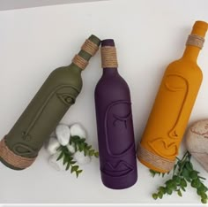 three different colored bottles sitting next to each other on top of a white countertop