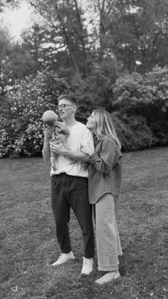 a man and woman holding a baby in their arms while standing next to each other