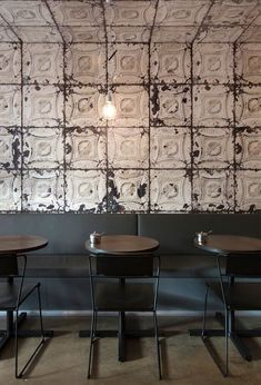 three tables and two chairs in front of a wall