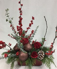 a vase filled with red flowers and greenery