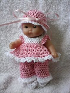 a small doll wearing a pink crocheted dress and hat