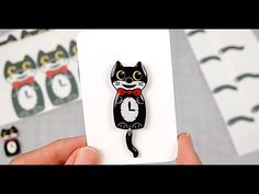 a person holding up a black and white cat brooch