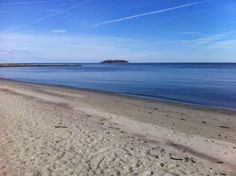 there is a sandy beach with footprints in the sand and an island in the distance