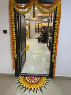 an entrance decorated with orange and yellow garlands, flowers and candles on the floor