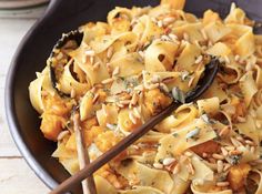 a bowl filled with pasta and nuts on top of a table