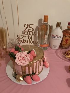 a cake with pink frosting sitting on top of a table next to liquor bottles