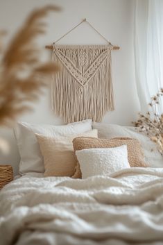 a white bed topped with lots of pillows next to a wall mounted hanging on the wall