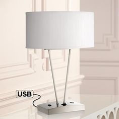 a white table lamp sitting on top of a glass table next to a mirror and wall