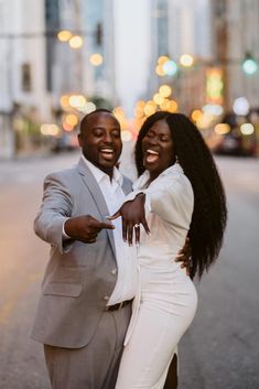 a man and woman posing for a photo in the middle of an empty city street