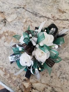 a bridal bouquet with white flowers and green leaves on a marble countertop top