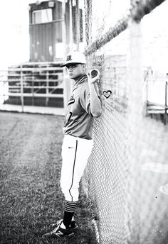 a young baseball player is leaning against the fence