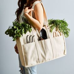 a woman holding a tote bag filled with vegetables