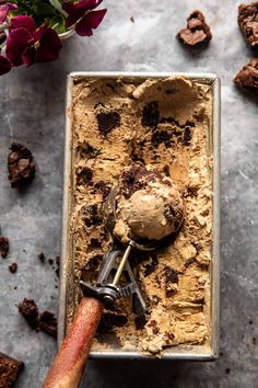 an ice cream sundae in a metal pan with chocolate chunks and flowers on the side