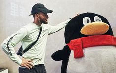 a man standing next to a penguin mascot