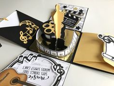 a birthday cake with gold and black decorations on it's side, surrounded by other greeting cards