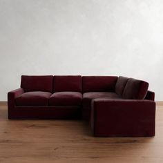 a red couch sitting on top of a hard wood floor next to a white wall