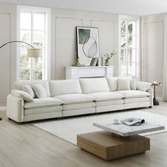 a living room with white furniture and large windows