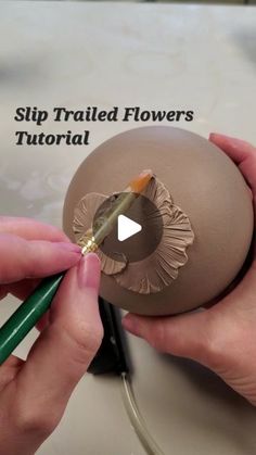 someone is painting an easter egg with flowers on the side and writing it in white