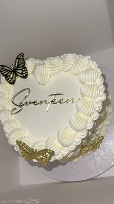 there is a white cake with gold butterflies on it and the name serent written in cursive writing