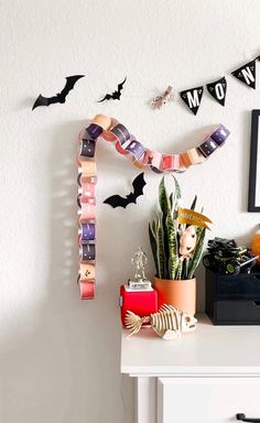 halloween decorations on a white dresser in a room with black and white decor, including bats hanging from the wall