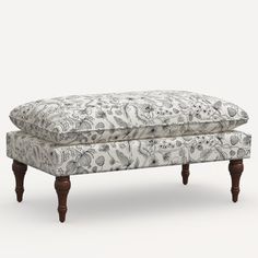 an upholstered bench with wooden legs and a floral pattern on the backrest