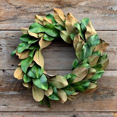 a wreath made out of green leaves sitting on top of a wooden table