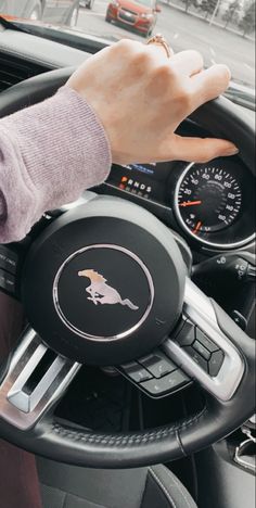 a person driving a car with their hand on the steering wheel and dashboard gauges