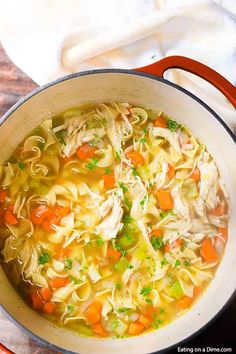 a pot filled with chicken noodle soup on top of a table