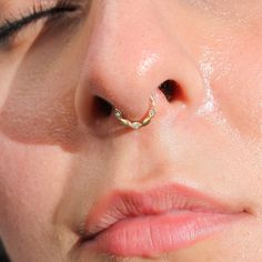 a close up of a person with a nose ring on their nose and one eye open