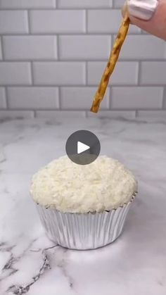 a cupcake being dunked with white frosting