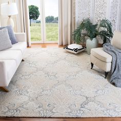 a living room filled with furniture and a white rug on top of a hard wood floor