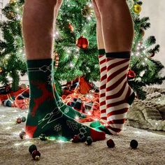 a person standing in front of a christmas tree wearing green socks with red and white stripes