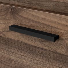 a close up of a drawer handle on a wooden cabinet with dark wood grained finish