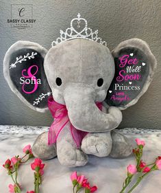 an elephant with a tiara sitting next to pink flowers